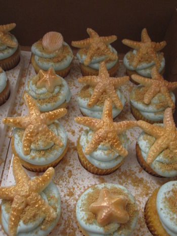 Vanilla bean cupcakes with vanilla buttercream.  Shells and starfish are made from white chocolate and painted with petal dusts.  Sand is a mixture of brown sugar and graham cracker crumbs.