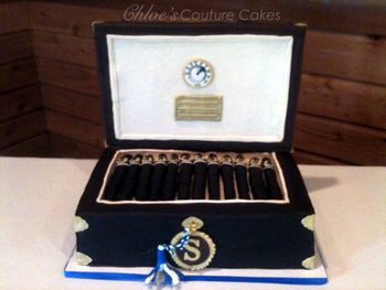 This is a humidor thats chocolate cake with chocolate Ganache and Chocolate SMBC.  The lid is RCT's covered in modeling chocolate and gumpaste.  Hand painted Hygometer, Cigars are chocolate cake rolled in fondant.  Humidor box is covered in Chocolate fondant.  Gumpaste key, tassel and S monogram