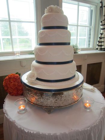 Stacked 4 tier Elegant classic and traditional American wedding cake. covered with sugarpaste and the sugar roses cake topper are made from gumpaste.