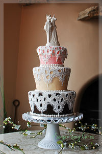 5"/7"/9" fondant cake with lace overlay of fondant overpiped with royal.  Porcelain topper was inspiration for this fairy-tale, whimsical wedding.  Bottom cake was dark chocolate with vanilla bean SMBC, top two tiers were vanilla rose with vanilla bean SMBC.