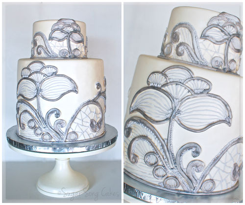 Double barrel 10" round with 6" topper.  Fondant covered with hand crafted lace made of fondant and royal icing that was painted with silver luster.  [bride provided photo that i used for inspiration (varying design as much as she'd allow), but it had no credit.]