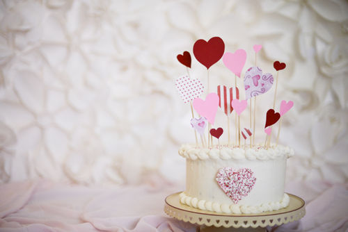 A strawberry cake with cream cheese icing.  very simple paper decorations and a sprinkle heart.