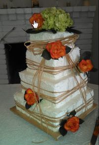 A 4 tier Square Wedding Cake (12", 10", 8", & 6"). Chocolate cake with chocolate mousse filling, and White cake with vanilla mousse filling, all covered in buttercream icing. The bride provided the raffia and the fresh flowers that were added on location.