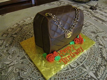 My very 1st purse cake! It is styled after Chanel. All edible except for the chain handles. This is not fondant or gumpaste. It is frosted with Pastry Pride and then covered with a thin sheet of brown Icing Images edible paper. It was quilted when the sheet was semi soft from the moisture of the whipped cream. The edging is modeling chocolate. No nasty fondant to peel off. I am very happy with the way it came out!