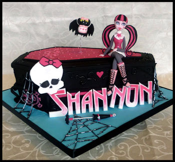 Monster High Draculaura Birthday cake. Coffin shaped cake. Figure hand modelled in fondant and modelling paste then hand painted. All decorations edible, including figure, bat, lettering, skull etc.