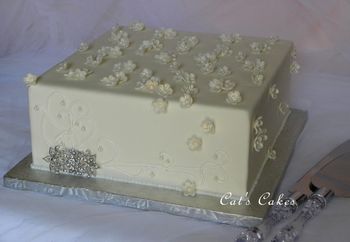 Lemon Chiffon with Raspberry filling covered in MMF with royal icing piping/trim and luster dusted flowers with pearl candy center. The broach is actually a reproduction of the Bride's Great Grandmothers wedding broach.