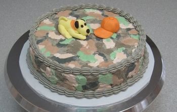 camo cake with fondant puppy & hat.  First error was using SMBC, should have used AMBC.  The icing wouldn't press down smooth, it just got sticky.  Live & learn.  I'll try it again later. Actually I don't want to eat this, it's too ugly.  I just want to put it in the wash machine with some Tide detergent.
