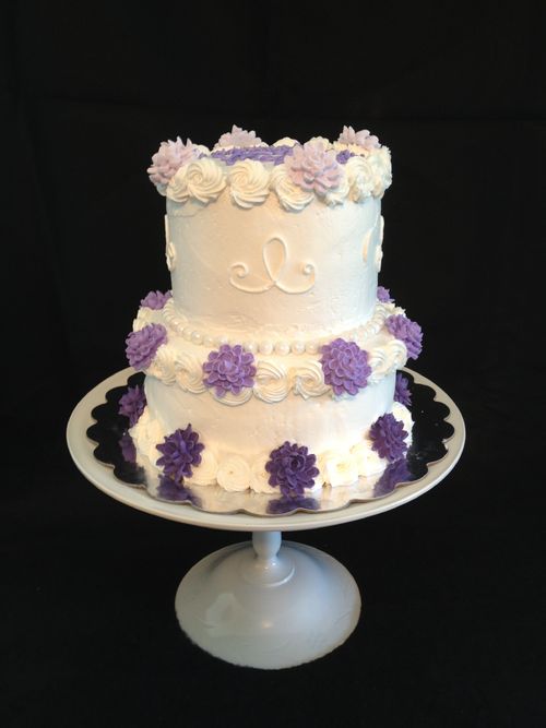 This is a 2 tiered cake.  The bottom layer is an 8"  classic white cake and the top tier is a 6" chocolate cake, made from scratch recipe.  The icing is a light, creamy buttercream with a rosette boarder.  Edible pearls surround the boarder of the top and bottom layers like jewelry.  The chrysanthemum flowers are piped with royal icing and placed on the cake in an ombre color style.  The cake is displayed on a cake stand crafted by myself from odd glassware and painted white.