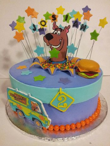 11" round frosted in Pastry Pride. Stars, Scooby and the mystery machine van are edible images mounted on a gumpaste plaque. Cheeseburger is fondant and dog collar is modeling chocolate