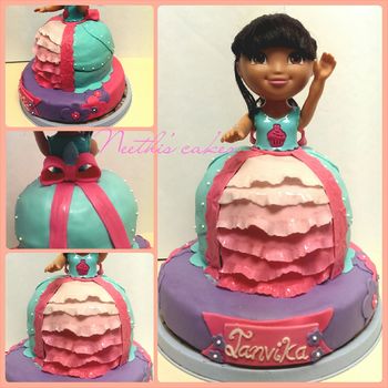 "Dora cake" A doll cake made for a Dora themed birthday party.  -The bottom 9 in cake tier is made with chocolate chip cake -The dress cake is made with a yellow- chocolate chip cake. The cake is decorated using homemade MMF and chocolate butter-cream frosting.  The dress is made using teal colored MMF and the ombre frills are made using gradient colored MMF.