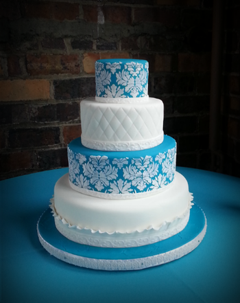 I recently did this wedding cake for the son of a friend.  The bride didn't want a topper or anything else, but I'd have liked a large peony or rose on top.  The fondant is Albert Uster FondArt, a product that I love.  I matched the blue to David's Bridal Malibu Blue.  The damask is royal icing stenciling.  The embossed ribbon is a new product from Wilton and I love it--deep embossing, flexible, and very time saving.
